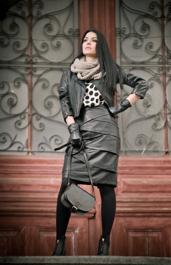 La mujer joven atractiva en tiro de la moda del invierno con hierro labrado adornó puertas en fondo. Hembra de moda hermosa imágenes de archivo libres de regalías La mujer joven atractiva en tiro de la moda del invierno con hierro labrado adornó puertas en fondo. Hembra de moda hermosa imágenes de archivo libres de regalías