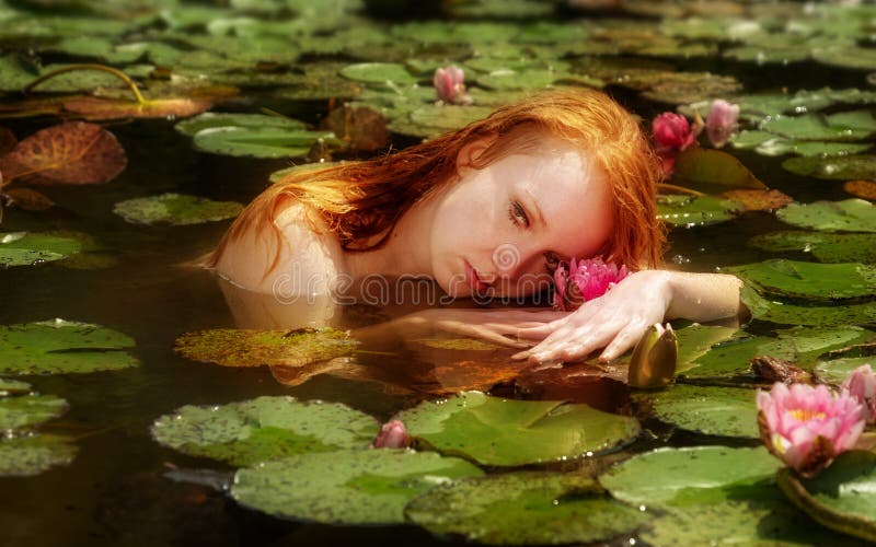 La mujer joven blanda Ofelia del pelirrojo flota sensual atractivo en el agua, el lago, la charca, el pantano y jugar con los wat fotografía de archivo La mujer joven blanda Ofelia del pelirrojo flota sensual atractivo en el agua, el lago, la charca, el pantano y jugar con los wat fotografía de archivo