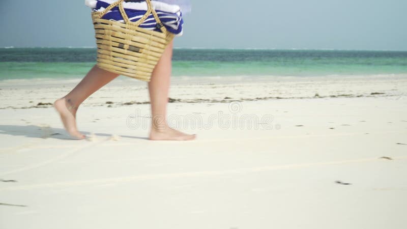 La mujer joven camina descalzo en la playa a lo largo del océano