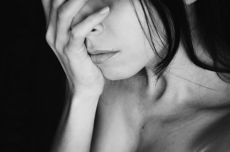 La mujer joven cubre su cara con blanco del negro de la mano fotos de archivo libres de regalías La mujer joven cubre su cara con blanco del negro de la mano fotos de archivo libres de regalías