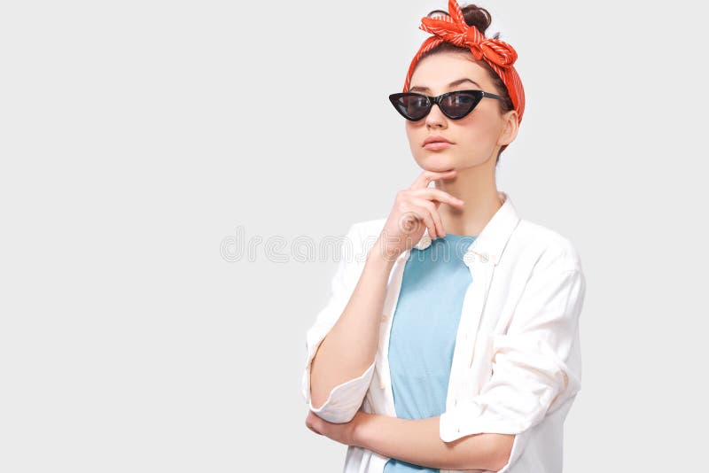 La mujer joven de la morenita seria hermosa lleva las lentes de sol negros, la camisa blanca y la venda roja de moda fotografía de archivo libre de regalías La mujer joven de la morenita seria hermosa lleva las lentes de sol negros, la camisa blanca y la venda roja de moda fotografía de archivo libre de regalías
