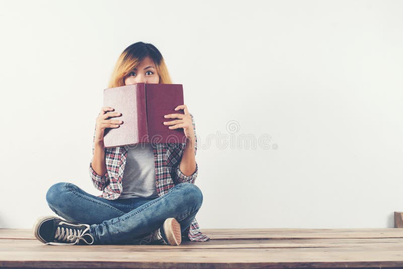La mujer joven del inconformista tomó el libro de su cara con la timidez, whe foto de archivo La mujer joven del inconformista tomó el libro de su cara con la timidez, whe foto de archivo