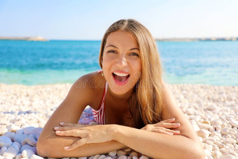 La mujer joven emocionada que miente en los guijarros vara Retrato ascendente cercano de la muchacha feliz en sus vacaciones de v fotografía de archivo La mujer joven emocionada que miente en los guijarros vara Retrato ascendente cercano de la muchacha feliz en sus vacaciones de v fotografía de archivo