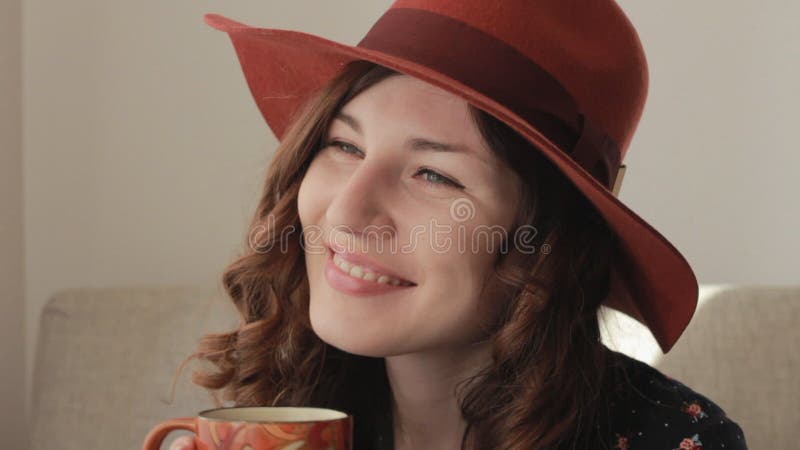 La mujer joven en sombrero bebe el café