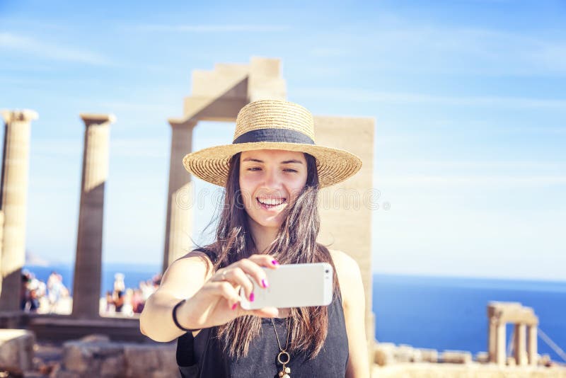 La mujer joven hermosa en un sombrero hace el selfie en el fondo de foto de archivo La mujer joven hermosa en un sombrero hace el selfie en el fondo de foto de archivo