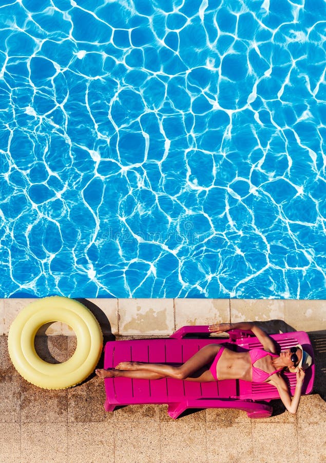La mujer joven hermosa que ponía encendido sunbed en el poolside imagen de archivo libre de regalías La mujer joven hermosa que ponía encendido sunbed en el poolside imagen de archivo libre de regalías