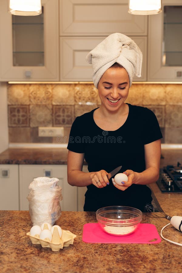 La mujer joven que prepara la pasta, cuece las galletas imagen de archivo La mujer joven que prepara la pasta, cuece las galletas imagen de archivo