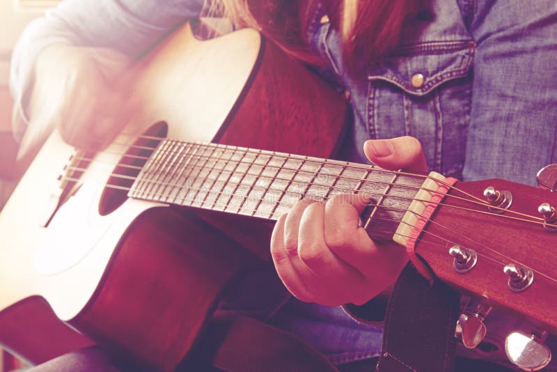 La mujer joven que toca la guitarra y que sostiene los fingeres chord primer p imagen de archivo La mujer joven que toca la guitarra y que sostiene los fingeres chord primer p imagen de archivo