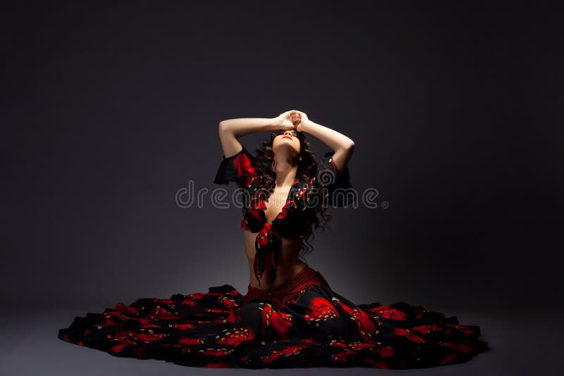 La mujer joven se sienta en traje negro y rojo gitano imagen de archivo La mujer joven se sienta en traje negro y rojo gitano imagen de archivo