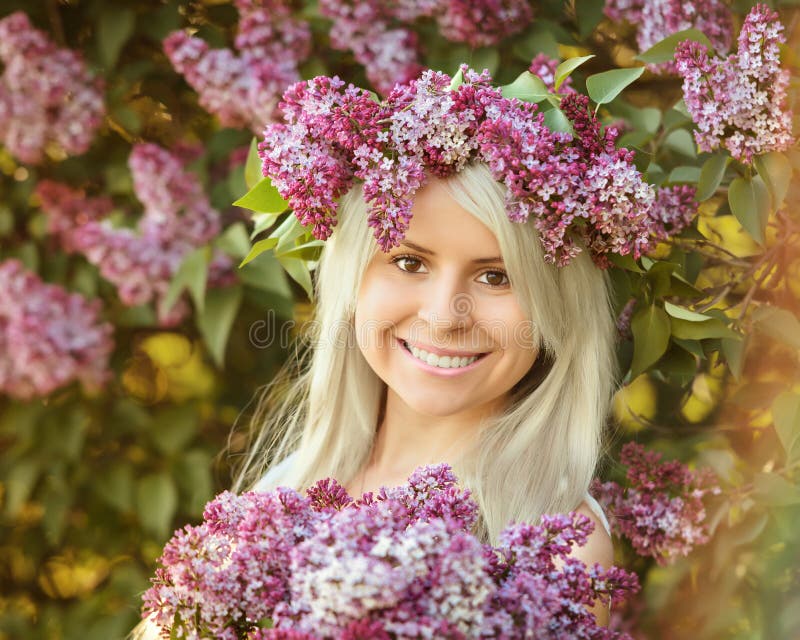 La mujer joven sonriente hermosa está llevando la guirnalda de las flores de la lila fotos de archivo La mujer joven sonriente hermosa está llevando la guirnalda de las flores de la lila fotos de archivo