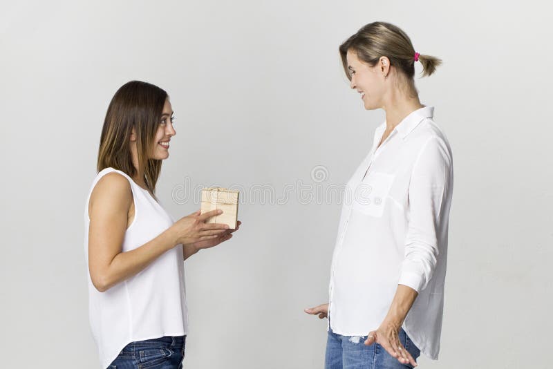 La mujer joven sorprendida consigue un regalo de su amigo Amigos femeninos felices y sonrientes imagen de archivo libre de regalías La mujer joven sorprendida consigue un regalo de su amigo Amigos femeninos felices y sonrientes imagen de archivo libre de regalías