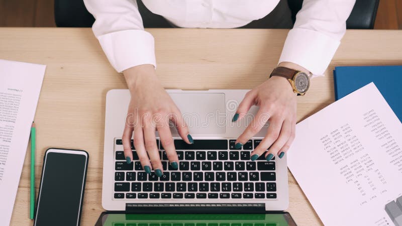 La mujer joven utiliza el ordenador en su lugar de trabajo en oficina