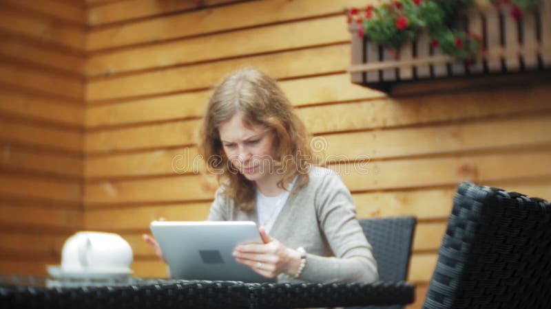 La mujer joven utiliza una tableta y el teléfono, bebe té en una barra del café almacen de video