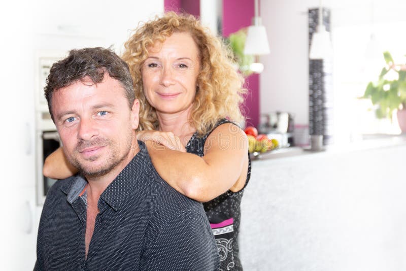 La mujer madura mayor abraza a su marido en la casa imagen de archivo La mujer madura mayor abraza a su marido en la casa imagen de archivo