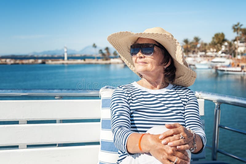 La mujer mayor elegante hermosa viaja en un yate, en un backgro imagenes de archivo La mujer mayor elegante hermosa viaja en un yate, en un backgro imagenes de archivo