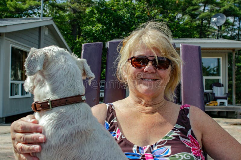 La mujer mayor positiva está disfrutando de tiempo con su perro imagen de archivo La mujer mayor positiva está disfrutando de tiempo con su perro imagen de archivo