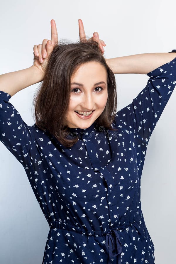 La mujer morena feliz muestra los estirones con sus fingeres y con una sonrisa que mira la cámara imágenes de archivo libres de regalías La mujer morena feliz muestra los estirones con sus fingeres y con una sonrisa que mira la cámara imágenes de archivo libres de regalías
