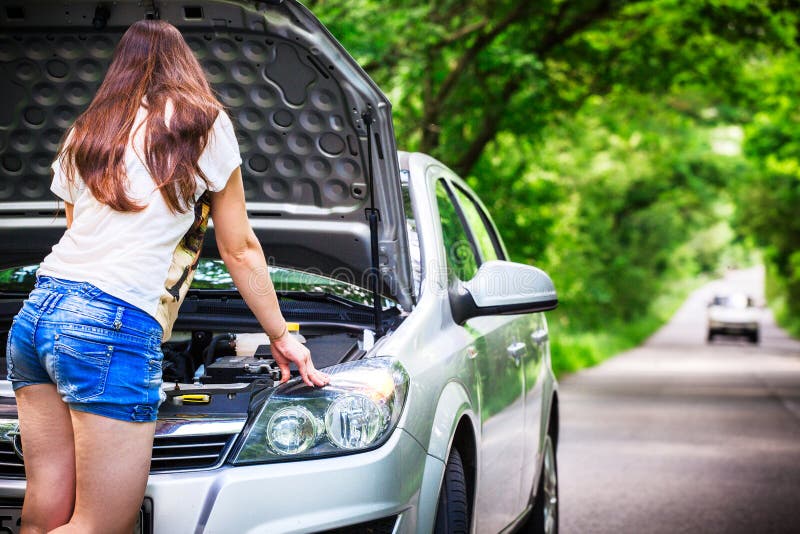 La mujer morena joven se coloca cerca de un coche de plata en el borde de la carretera Mujer cerca del coche con la capilla abier foto de archivo libre de regalías La mujer morena joven se coloca cerca de un coche de plata en el borde de la carretera Mujer cerca del coche con la capilla abier foto de archivo libre de regalías