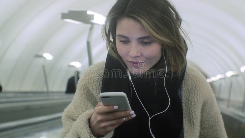 La mujer morena joven utiliza un tel? fono con los auriculares almacen de metraje de vídeo
