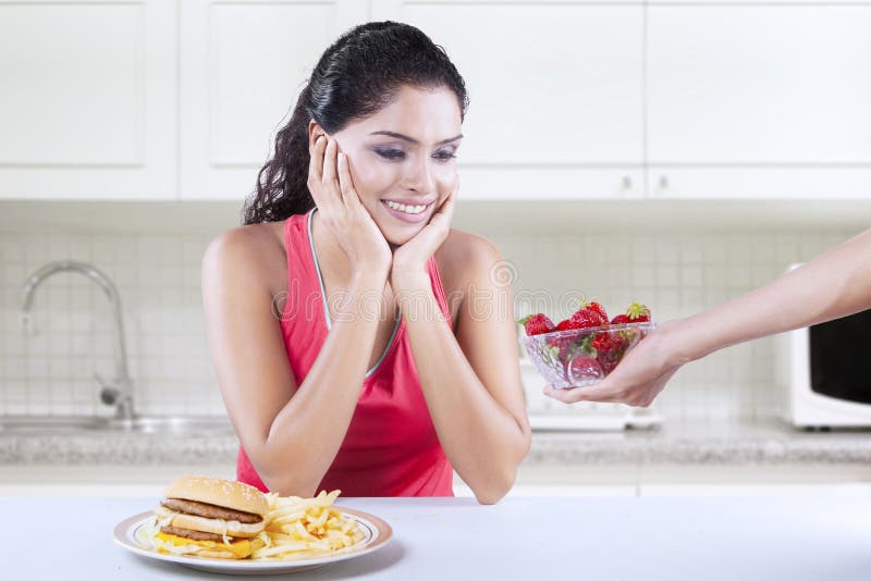 La mujer quiere la fresa bastante que la hamburguesa foto de archivo La mujer quiere la fresa bastante que la hamburguesa foto de archivo