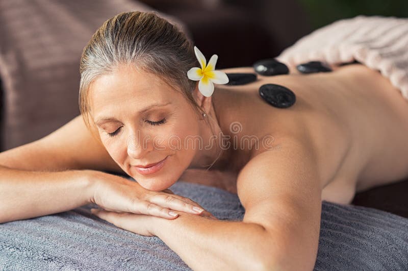 La mujer relajada con las piedras calientes encendido apoya imagenes de archivo La mujer relajada con las piedras calientes encendido apoya imagenes de archivo