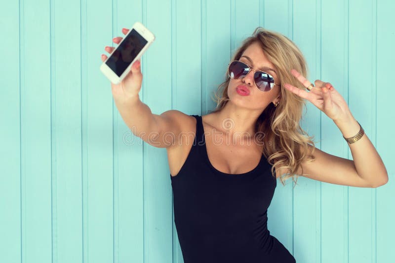 La mujer rubia en mono con el cuerpo perfecto que tomaba smartphone del selfie entonó el filtro del instagram fotos de archivo libres de regalías