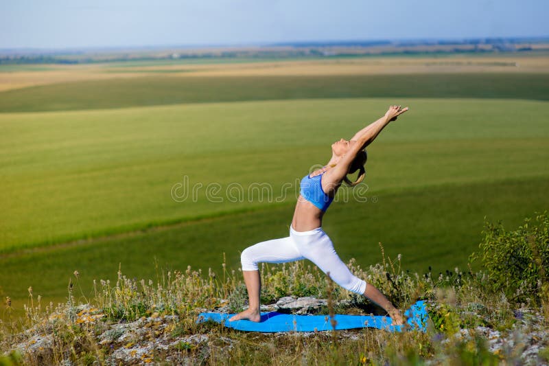 La mujer rubia hermosa joven que hace yoga ejercita en una roca foto de archivo libre de regalías La mujer rubia hermosa joven que hace yoga ejercita en una roca foto de archivo libre de regalías