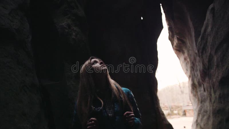 La mujer rubia joven asustada con caminar de la mochila perdió en la cueva oscura Aventura peligrosa, caminando Naturaleza asombr