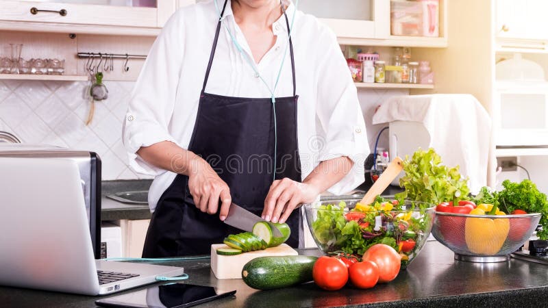 La mujer sana hace la ensalada de las verduras frescas con el aceite de oliva, tomate foto de archivo La mujer sana hace la ensalada de las verduras frescas con el aceite de oliva, tomate foto de archivo