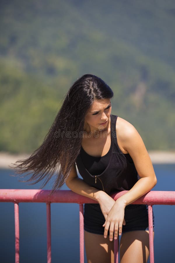 La mujer se sienta al borde de una presa foto de archivo libre de regalías La mujer se sienta al borde de una presa foto de archivo libre de regalías