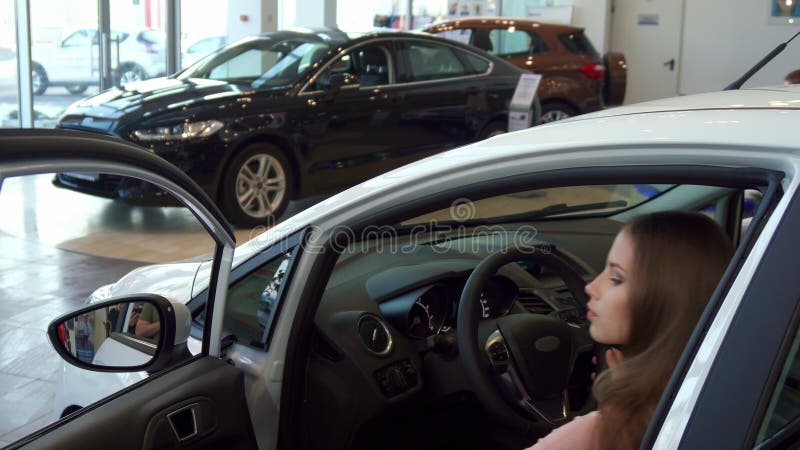 La mujer se sienta en el coche en la representación fotos de archivo La mujer se sienta en el coche en la representación fotos de archivo