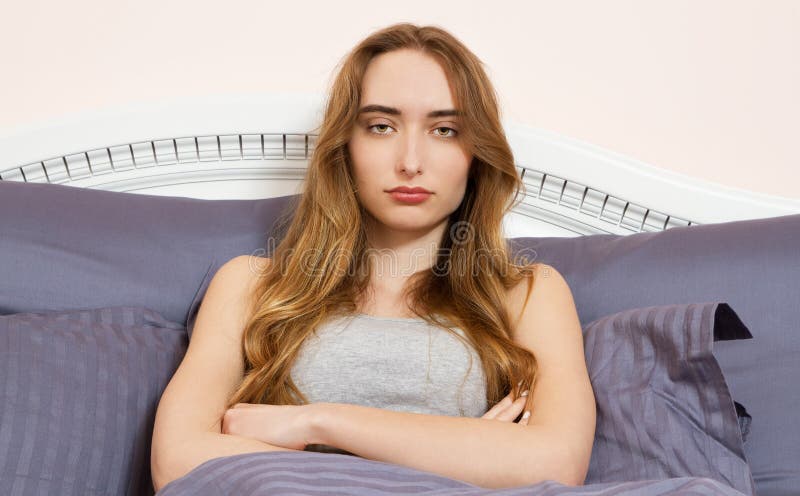 La mujer triste con los brazos cruz? sentarse en una cama en el dormitorio - ella tiene una jaqueca, un dolor de cabeza y un inso foto de archivo libre de regalías La mujer triste con los brazos cruz? sentarse en una cama en el dormitorio - ella tiene una jaqueca, un dolor de cabeza y un inso foto de archivo libre de regalías