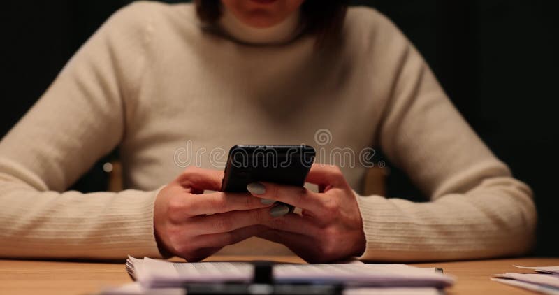 La mujer usa su teléfono en el escritorio tarde por la noche almacen de metraje de vídeo