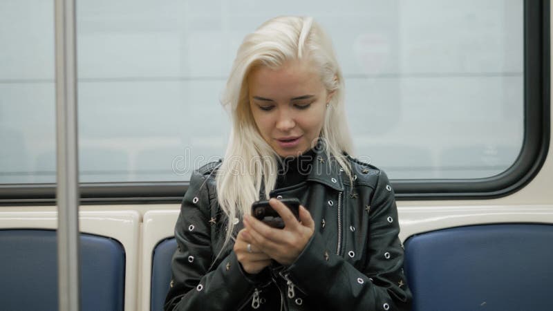 La mujer utiliza un smartphone en la chica joven del subterráneo en estudiante del transporte del tren almacen de video