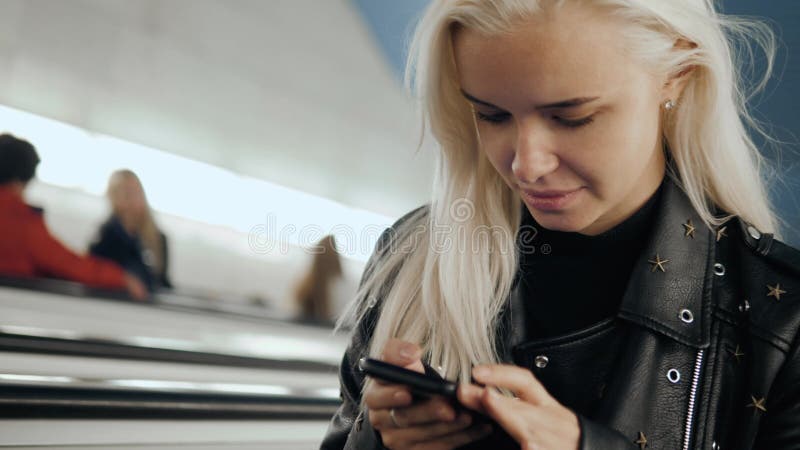 La mujer utiliza un smartphone en la chica joven del subterráneo en estudiante del transporte del tren almacen de video