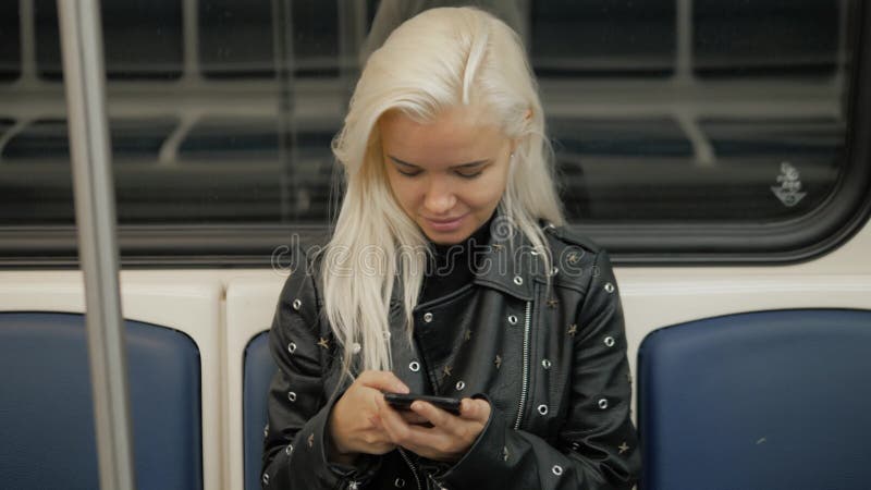 La mujer utiliza un smartphone en la chica joven del subterráneo en estudiante del transporte del tren almacen de video