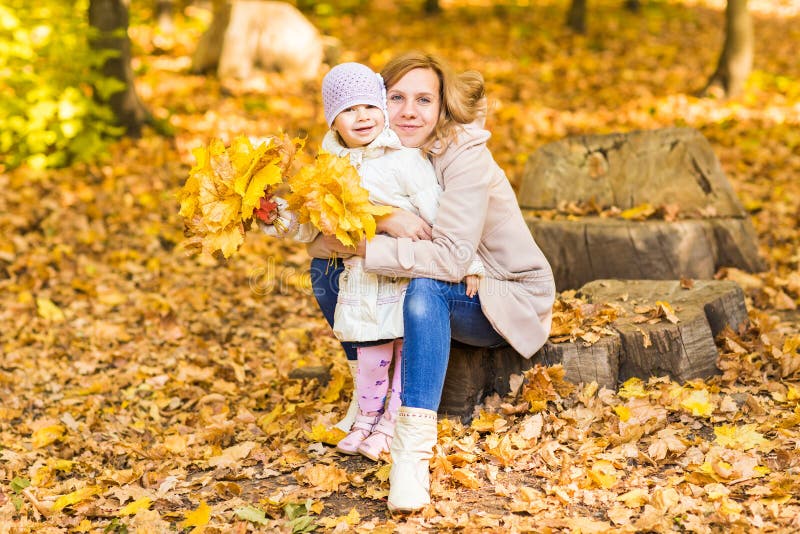 La mujer y la hija felices en el otoño parquean