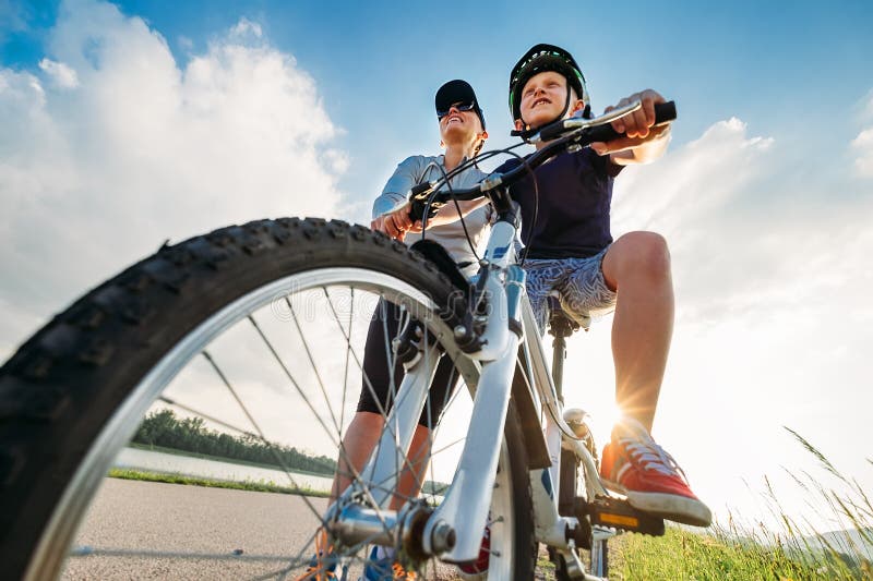 La mère aide son petit fils à commencer à monter une bicyclette photo stock La mère aide son petit fils à commencer à monter une bicyclette photo stock