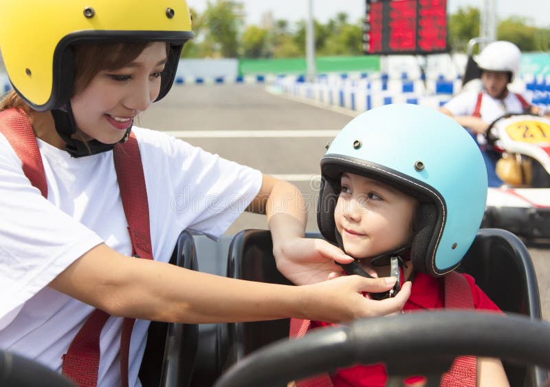 La mère attachant le casque de filles vont dessus kart photographie stock La mère attachant le casque de filles vont dessus kart photographie stock