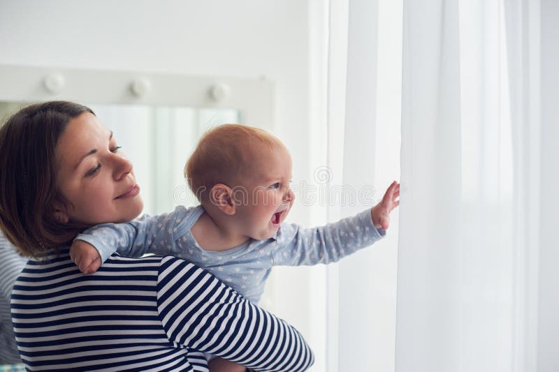 La mère continuent le bébé garçon riant d'épaule à la maison photographie stock La mère continuent le bébé garçon riant d'épaule à la maison photographie stock