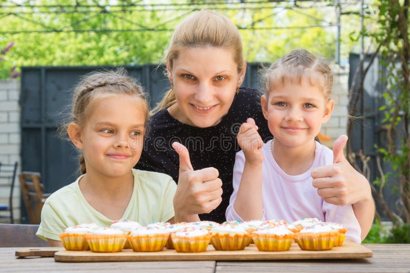 La mère et deux filles montrent des pouces-, et des petits gâteaux de Pâques de robe photographie stock libre de droits La mère et deux filles montrent des pouces-, et des petits gâteaux de Pâques de robe photographie stock libre de droits