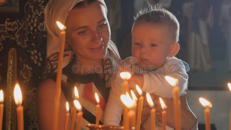La mère et le petit fils observe les bougies brûlantes dans l'église