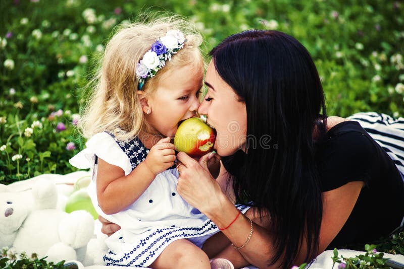 La mère et son enfant apprécient le premier ressort, mangeant la pomme, heureuse photo stock La mère et son enfant apprécient le premier ressort, mangeant la pomme, heureuse photo stock