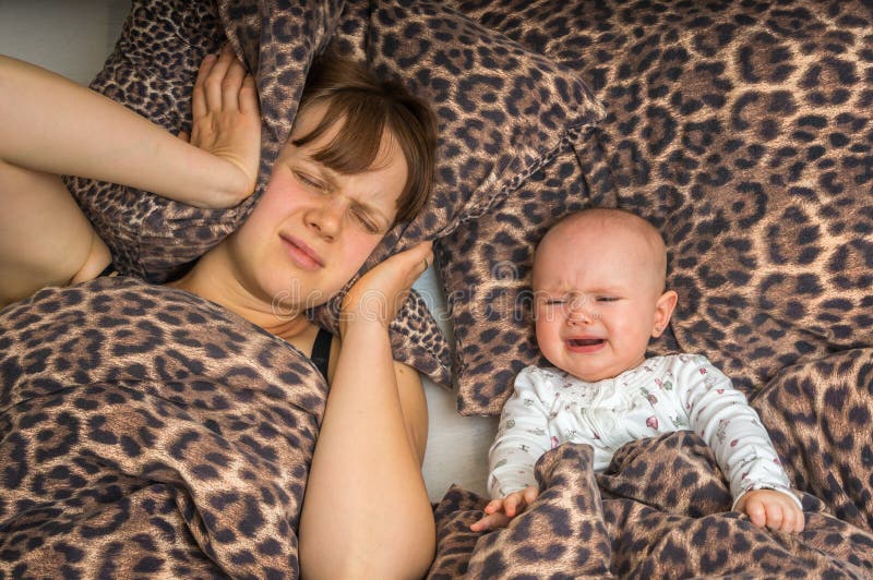 La mère fatiguée peut le ` t dormir parce que son bébé pleure photographie stock La mère fatiguée peut le ` t dormir parce que son bébé pleure photographie stock