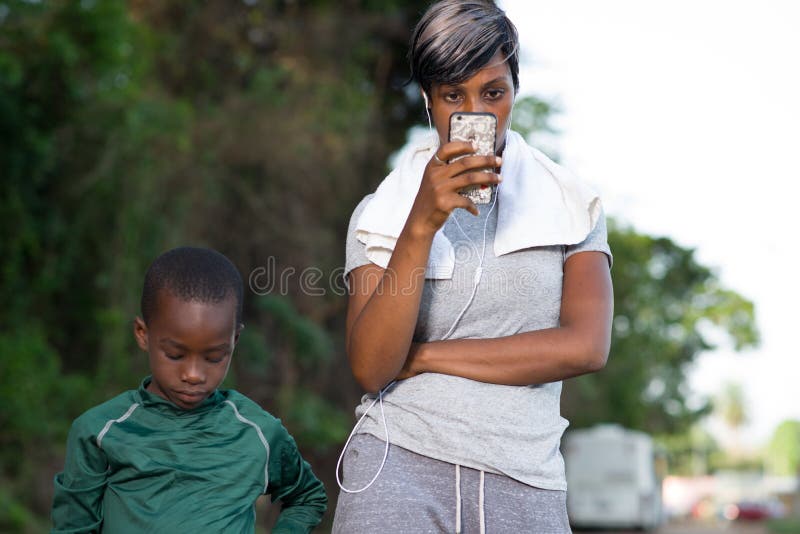 La mère regarde le téléphone tandis que son fils joue près de elle images libres de droits La mère regarde le téléphone tandis que son fils joue près de elle images libres de droits