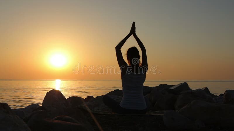 La méditation de matin, femme pratique le yoga sur le bord de la mer, tir sur la marque IV d'EOS 5D de Canon dans le mouvement le