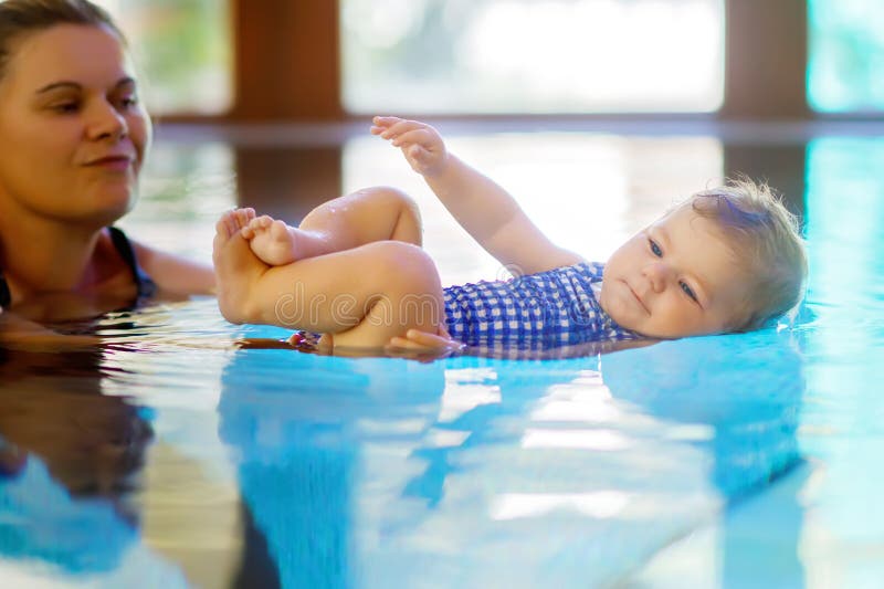 La natación feliz de la madre con la hija adorable linda del bebé en balneario del gasto de la piscina vacations fotografía de archivo libre de regalías La natación feliz de la madre con la hija adorable linda del bebé en balneario del gasto de la piscina vacations fotografía de archivo libre de regalías