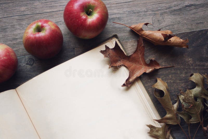 La natura morta di autunno con le mele, libro aperto e rimane il fondo di legno rustico