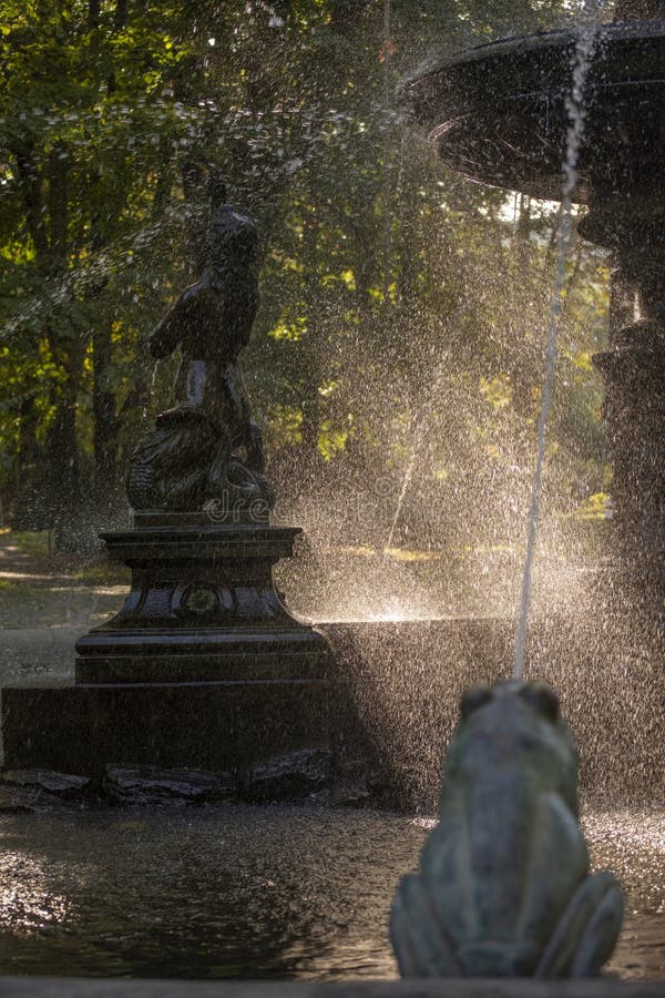 La nebbia d'acqua attraverso i raggi solari nella fontana del parco fotografie stock