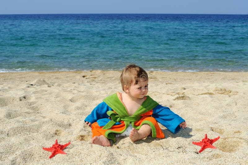 La neonata che gioca con il Mar Rosso stars sulla spiaggia fotografia stock libera da diritti La neonata che gioca con il Mar Rosso stars sulla spiaggia fotografia stock libera da diritti